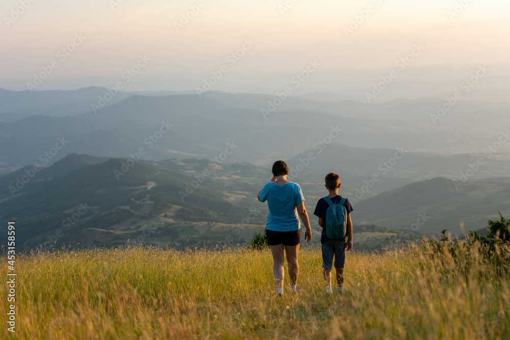 family travel concept- mother and son hiking in mountains. Mother and Son enjoying the view after a mountain hike during sunset