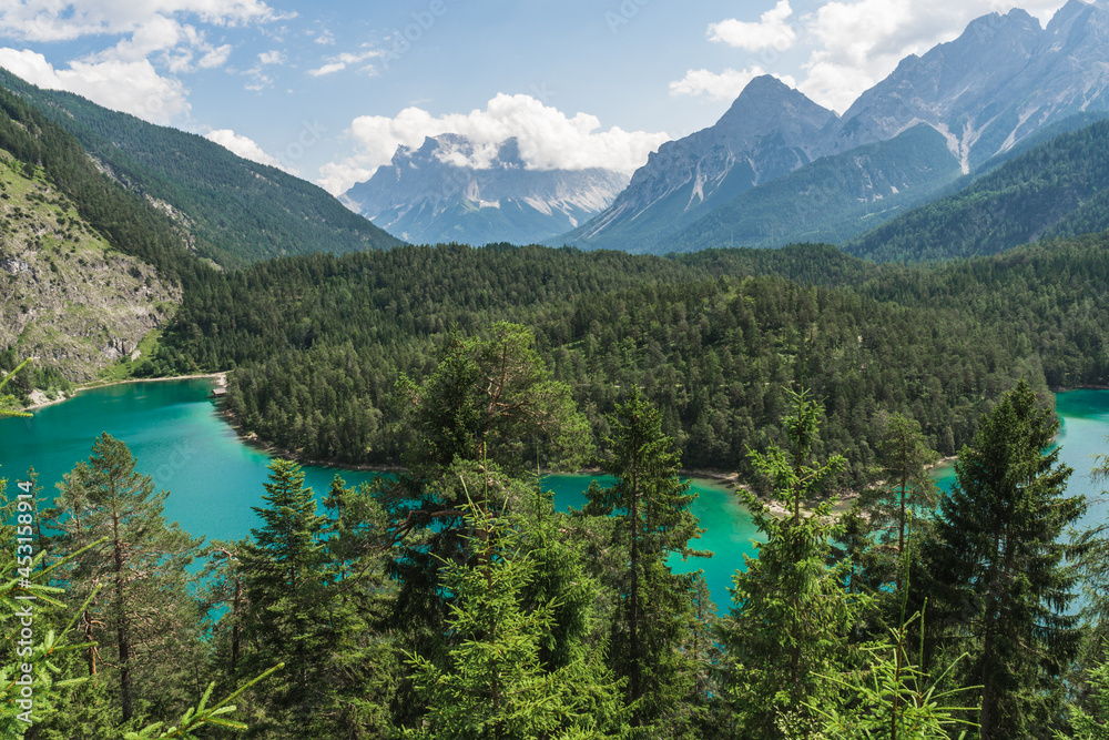 view to Germany's highest mountain Zugspitze and Austria's mountain Ehrwalder Sonnenspitze with an emerald green Blindsee lake in a foreground