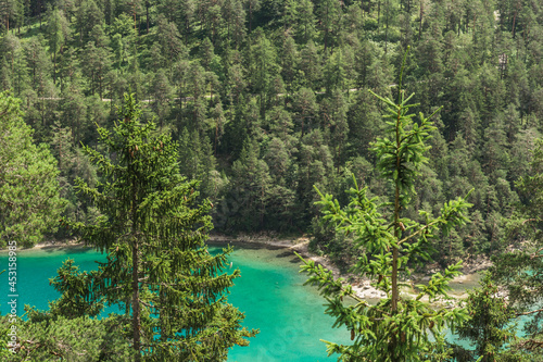 Two fir trees with an emerald green Blindsee lake in a background
