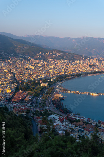 Alanya city (Turkey) harbor in the evening. Buildings. Bay with boats and ships. Mountains and sea. Vertical photo
