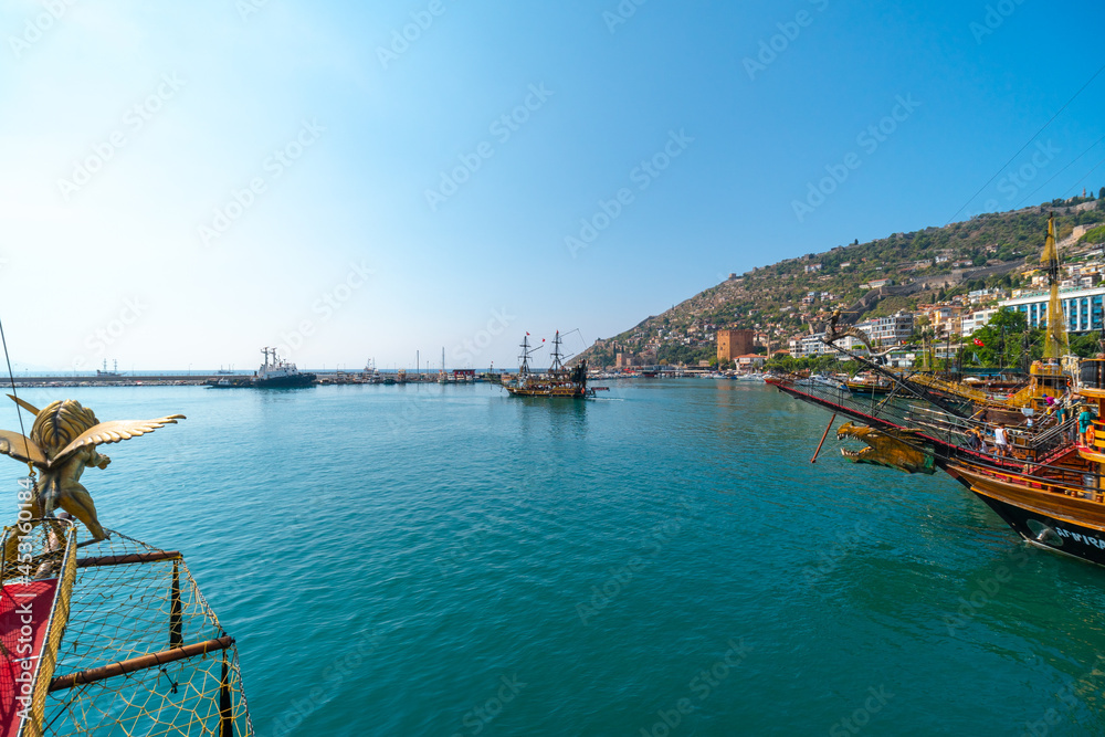 Old pirate ship on the water of Mediteranean sea. Tourist entertainment, coastal tour. Summer sunny day. Mountain shore of Alanya. Turkey.