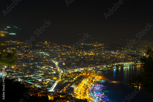 Kizil Kule tower in Alanya bay vith boats and ships, view from peninsula castle, Antalya district, Turkey. Famous tourism destination. Night cityscape.