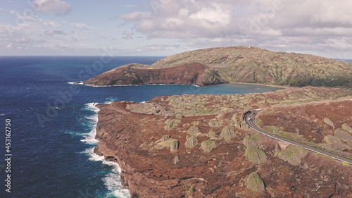 Flight over rocky coast of tropical island of Oahu Hawaii. View of Hanauma Bay. Kalanianaole Highway South Shore Oahu Hawaii Pacific Ocean Coastline. White clouds against blue sky. photo