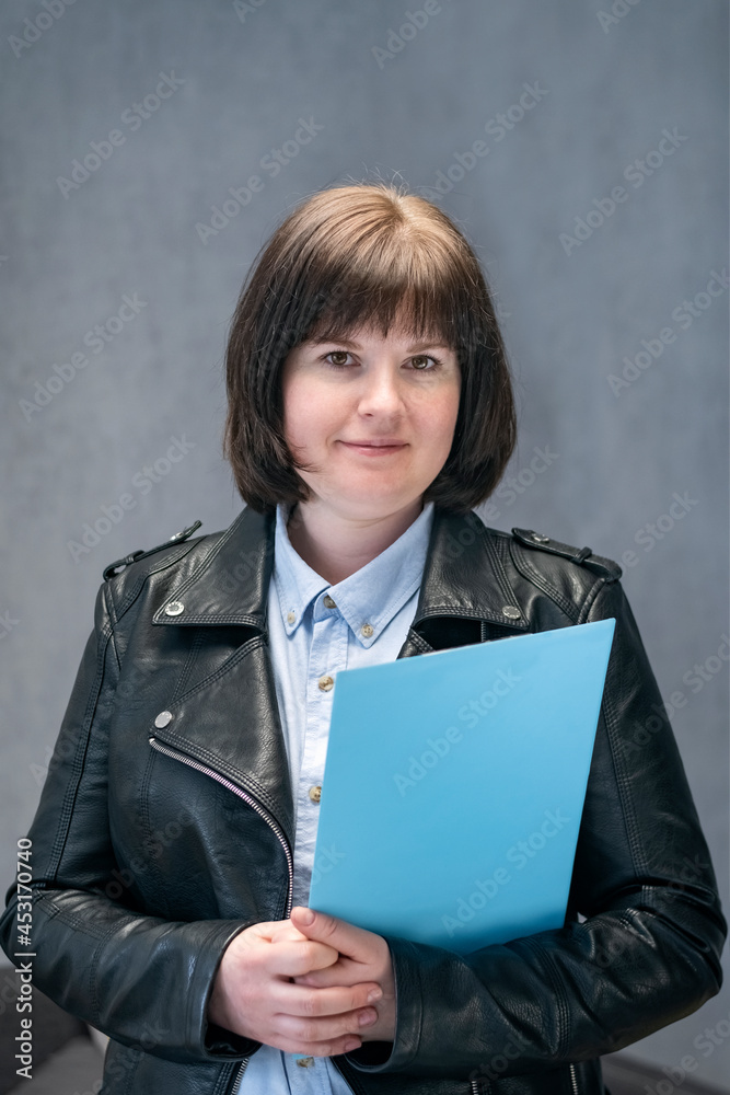 Young woman inspector in leather jacket with documents in hands. Modern business woman. Informal reception