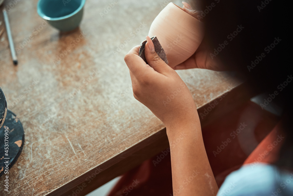 Obraz premium Female potter hands sanding clay pot in pottery workshop