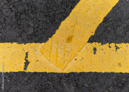 Shoe or trainer footprint in paint.  Yellow painted line with foot print left behind stood on whilst wet.  Black tarmac and bright yellow lined paint. photo