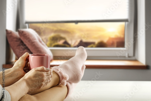 Slim young woman legs with socks and autumn window background. 