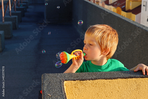 Blond boy makes soap bubbles. A four-year-old boy plays with soap bubbles.  photo