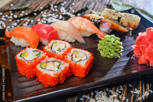 Various kinds of sushi and rolls served on black plate