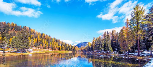 Obraz na płótnie Fantastic autumn landscape with a light crust on the surface of the pondbig stone and yellow larch on a background of snowy mountains in the Antorno Lake, Dolomites. Exotic amazing places. w salonie