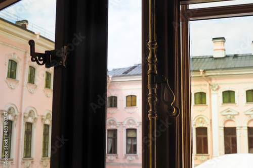 Brass handle on the old wooden opened window. Vintage metal window lever