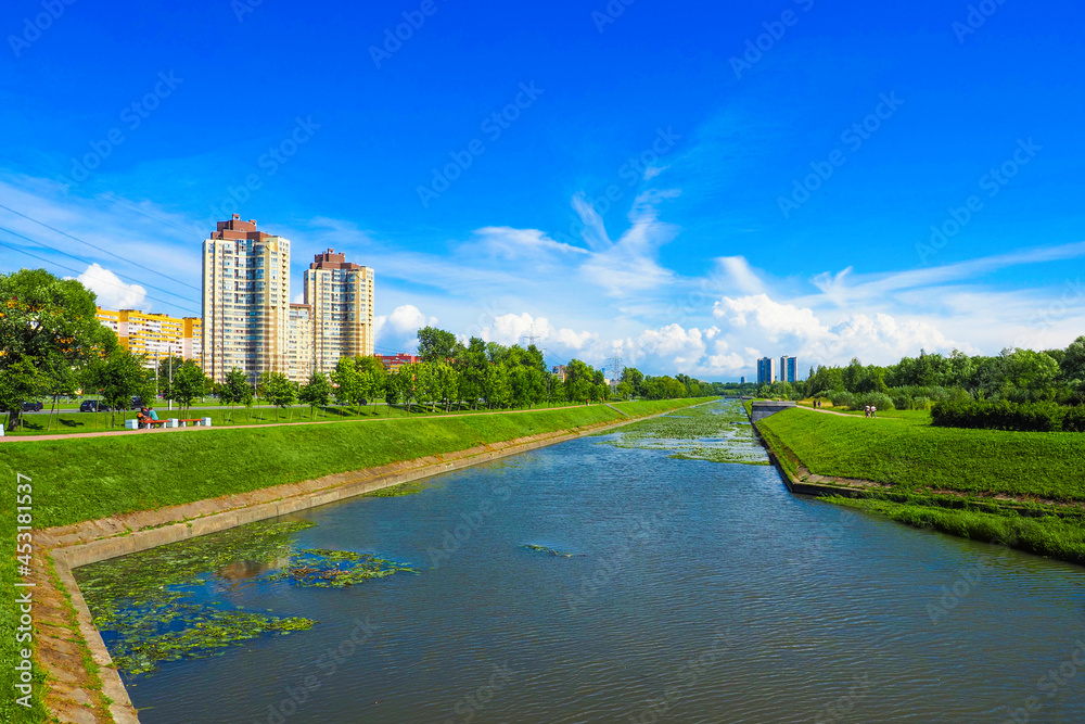 Green park with a canal in the city. Clear sunny summer weather. Duderhof Channel, Polezhaevsky Park, St. Petersburg, Russia