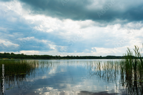 View from the coastline to the blue lake. Summer cloudy day. Nature landscape background