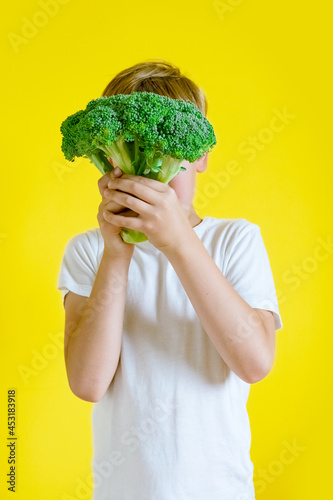 Adorable boy with broccoli on color background