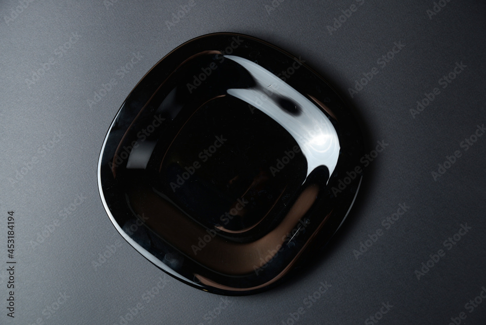 one black plate on dark background top view one black plate on dark background top view