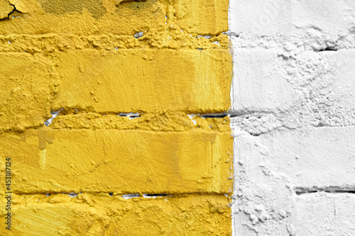 Yellow and white brick wall detail texture background. Old, painted, weathered and cracked bricks with concrete and stucco. Stripes on house wall. Close up, copy space photo