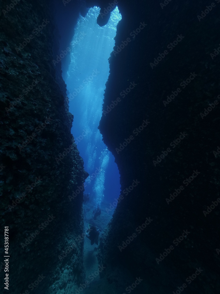 cave diving underwater scuba divers exploring caves and arches ocean scenery sun beams and rays background