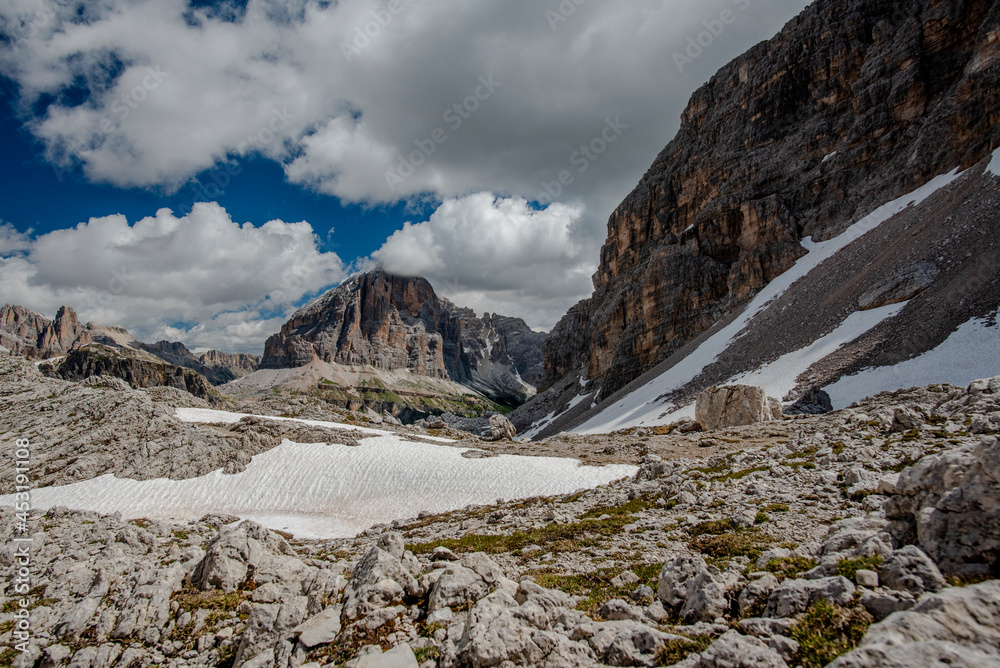 spring panorama of the green meadows of the Dolomites with snow and pink rocks at the Falzarego pass in Cortina d'Ampezzo Belluno Italy