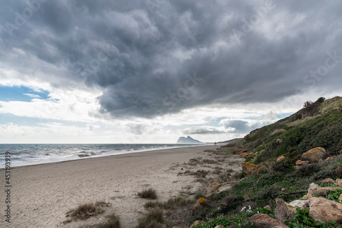 Paisaje de playa en La Linea de la Concepcion con nubes de tormenta y Pe  on de Gibraltar al fondo  Cadiz  Espa  a