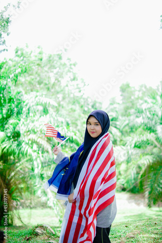 Muslim woman happy holding a Malaysian flag. Malaysia Independence Day.