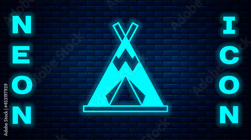 Glowing neon Traditional indian teepee or wigwam icon isolated on brick wall background. Indian tent. Vector