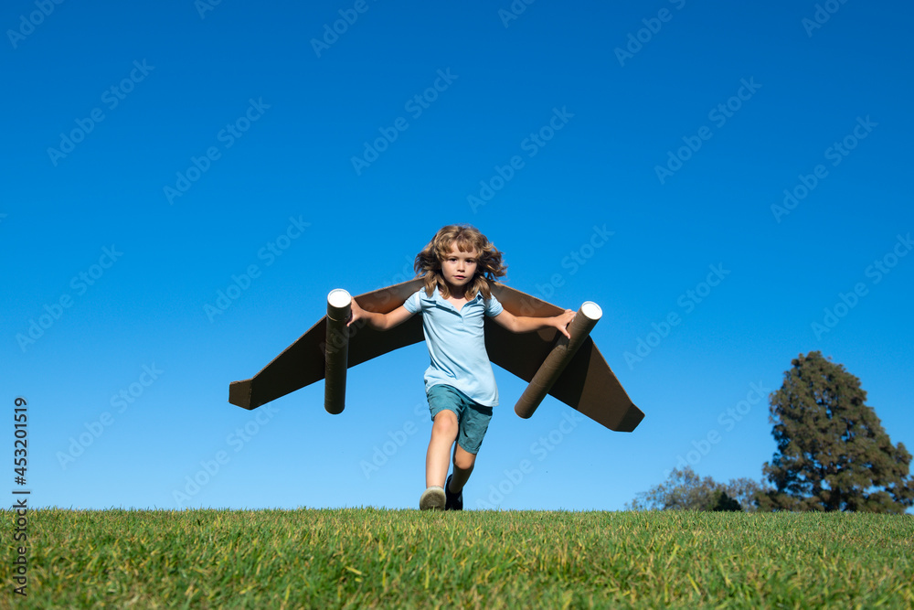 Boy child with wings at sky imagines a pilot and dreams of flying. Kids adventure, children freedom and imagination concept. Boy child with wings at sky imagines a pilot and dreams of flying. Kids adventure, children freedom and imagination concept.
