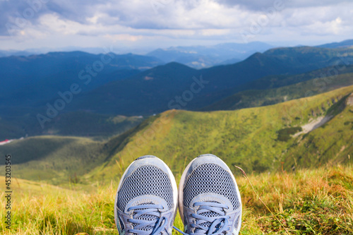 Blue sneakers of the traveler against the background of mountain landscapes. Tourism and travel concept. Selective focus
