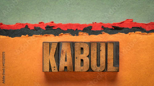 Kabul word abstract in vintage letterpress wood type printing blocks against abstract paper desert landscape in red, orange and black tones photo