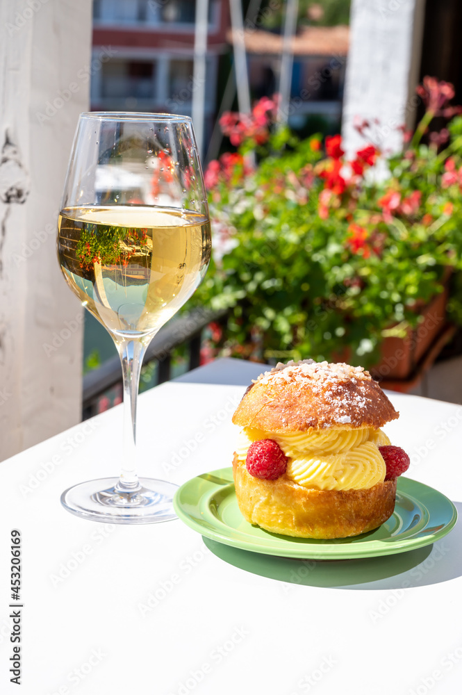 Tarte tropezienne or La Tarte de Saint-Tropez - dessert pastry consisting of filled brioche with cream and fresh berries.and glass of white wine