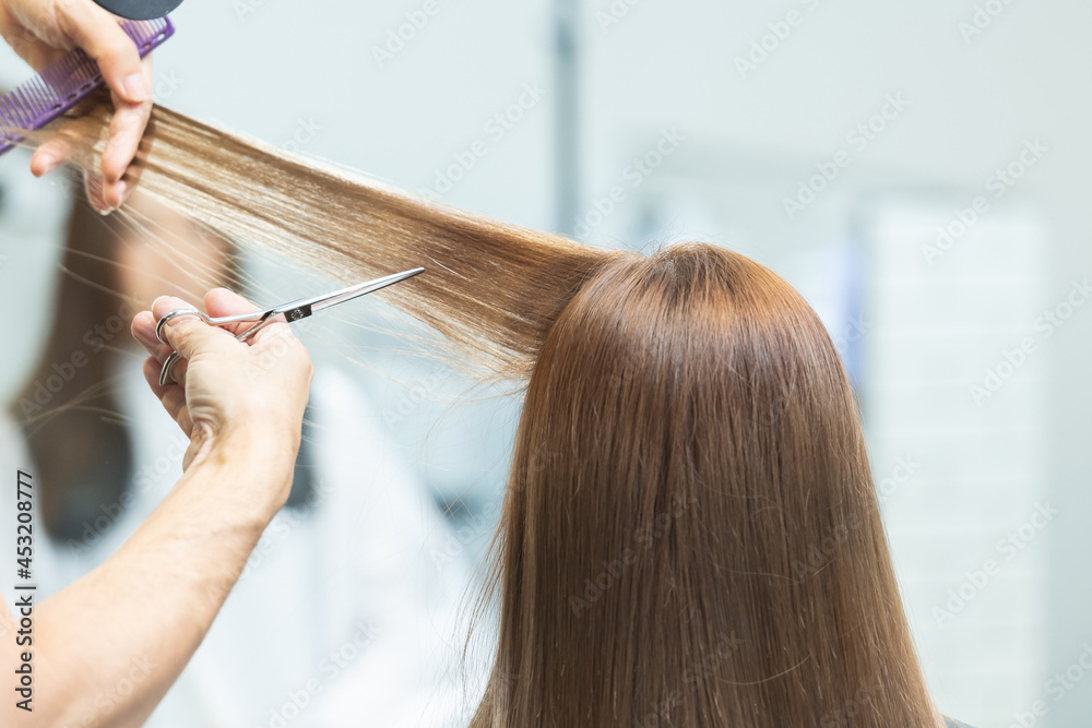 Fototapeta premium ヘアサロンで女性の髪の毛をカットするスタイリストの手元