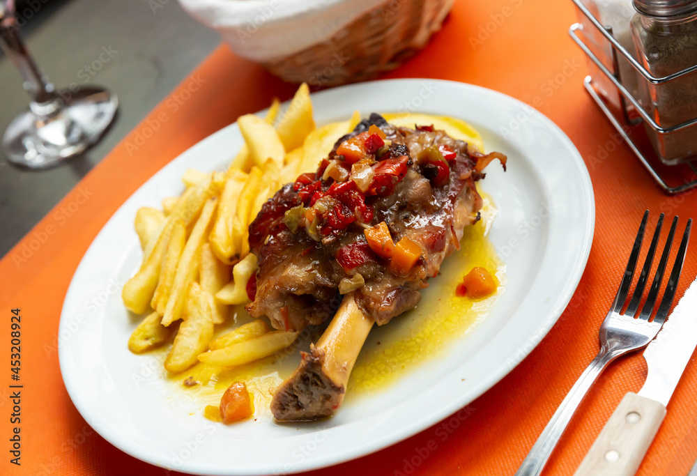 Close up of delicious baked with vegetables pork with french fries, served at plate