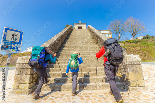 Two Adults and Child Pilgrims Ascending Stairs at City Entrance to Portomarin, along the Way of St James Pilgrimage Trail Camino de Santiago photo