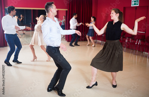 Adult dancing couples enjoying active dance in modern studio