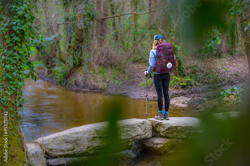 Pilgrim Girl Hiking on a Stone Bridge in Galicia Spain along the Way of St James Camino de Santiago Pilgrimage Trail