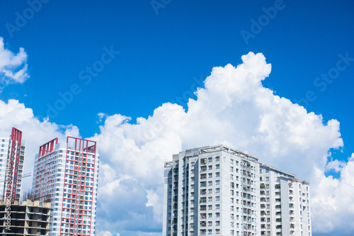 City landscape with sky clouds. Fluffy white clouds on blue sky  sunny summer day in the city