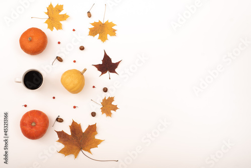 Yellow maple pumpkin leaves and a cup of black coffee on a white background. Autumn flat lay.