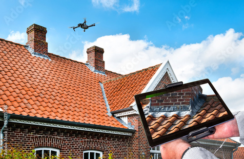 Fototapeta Drone in the air inspecting the roof over the house