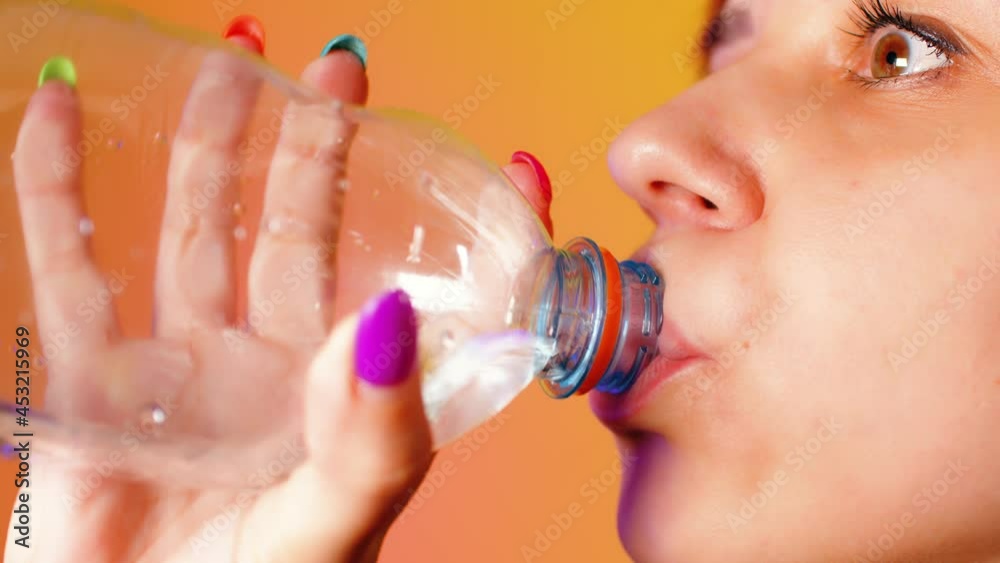 Beautiful woman taking a white round pill and washes it down with water from a plastic bottle. Beautiful woman taking a white round pill and washes it down with water from a plastic bottle.
