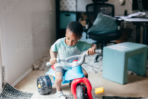 Black boy riding on toy tricycle  photo