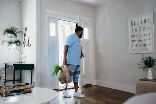 Black man with prosthetic leg bringing home groceries