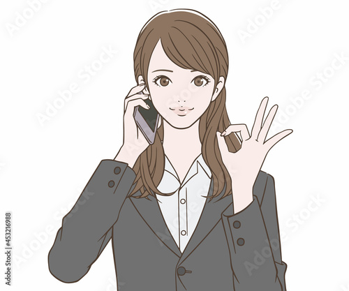 スマートフォンを持ち、OKマークをつくるスーツの女性