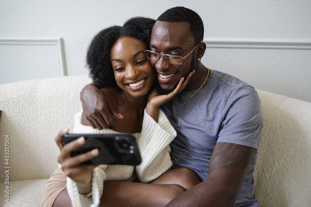 Smiling couple sitting on sofa and using smart phone Smiling couple sitting on sofa and using smart phone