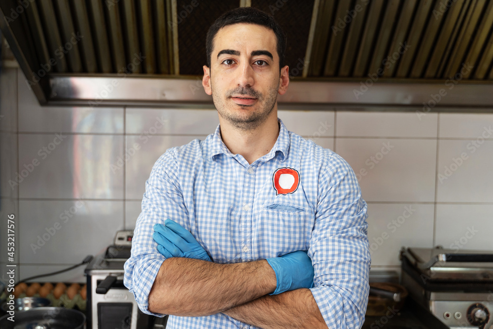 Front view portrait of adult caucasian man standing at work in cafe bar or fast food restaurant grill - Young serious entrepreneur small business owner front view portrait real people concept Front view portrait of adult caucasian man standing at work in cafe bar or fast food restaurant grill - Young serious entrepreneur small business owner front view portrait real people concept