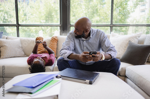 Father and son using smart phones on sofa photo