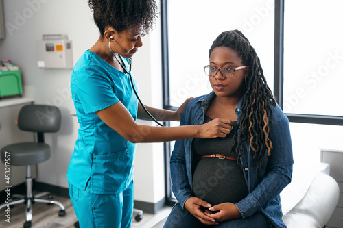 Black woman nurse checks vitals of pregnant patient