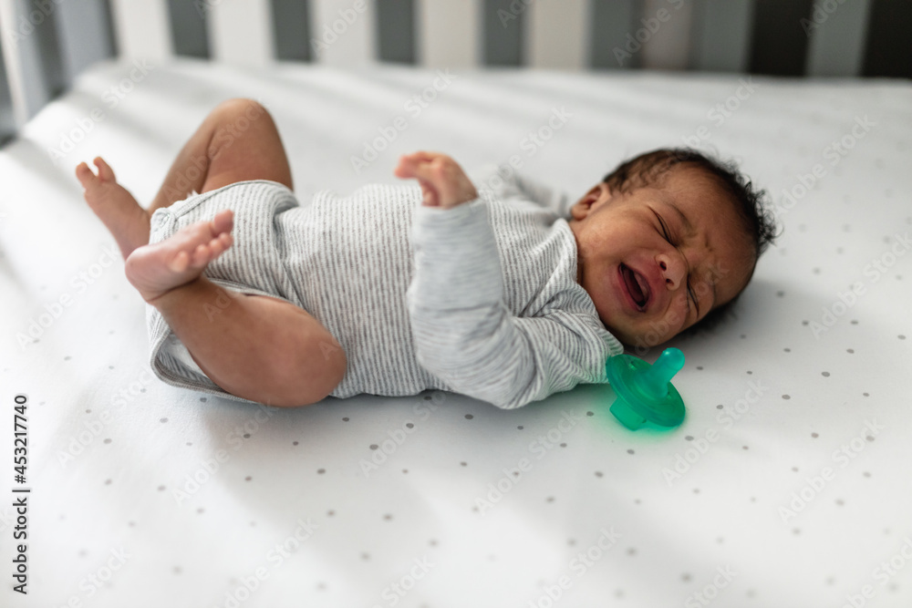 Newborn crying in baby crib, African American Stock Photo Adobe Stock