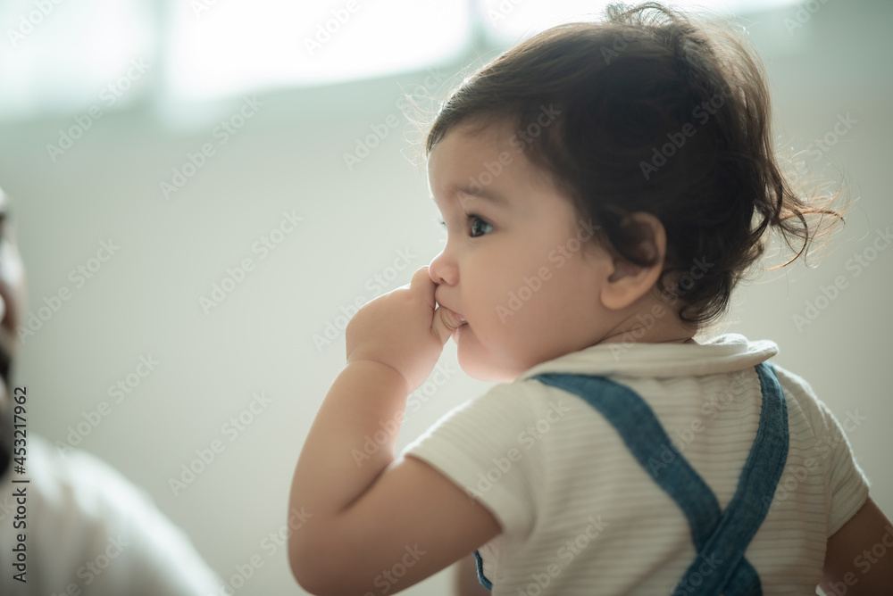 Cute little playful girl child learning to walk and stand by taking support of couch at home while looking away mischievously Cute little playful girl child learning to walk and stand by taking support of couch at home while looking away mischievously