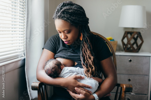 Black woman breastfeeding child at home photo