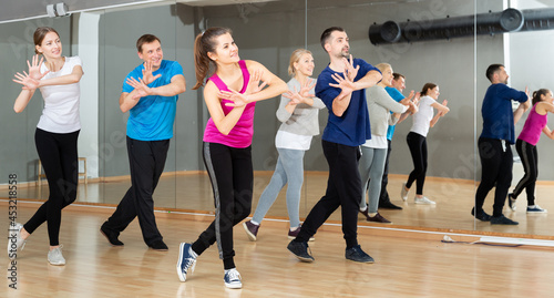 Cheerful people practicing vigorous lindy hop movements in dance class..