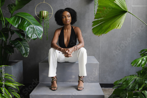 Elegant young woman sitting on steps among plants
